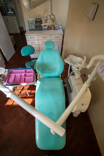 Vertical top view of a illuminated room of a dental clinic with a green stretcher and medical equipment