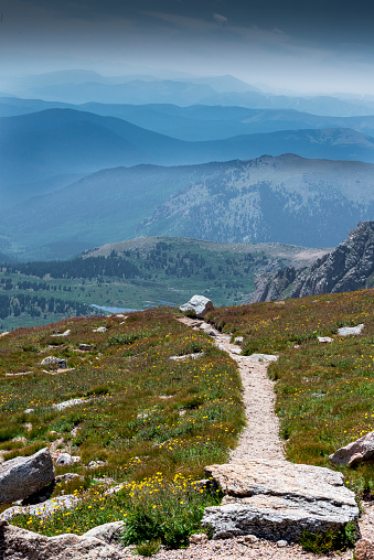 A dirt footpath on Mount Evans in Colorado leads to a drop-off and draws the viewers eyes to the distant mountains.