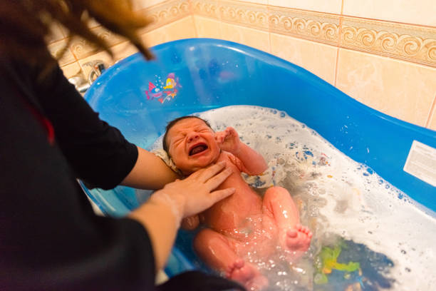 mother bathes her newborn baby for the first time in a baby bath - labour room imagens e fotografias de stock