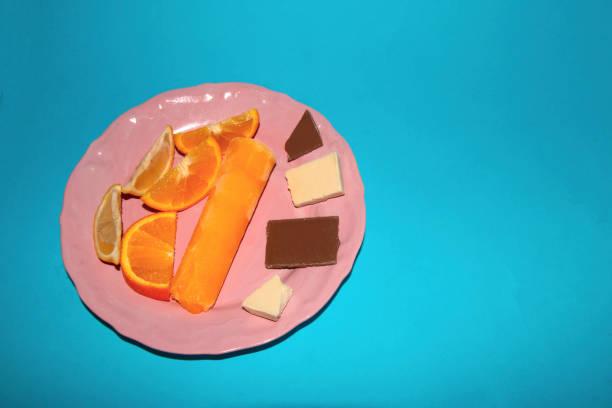 pink plate with slice orange ice cream and chocolate on a blue background, creative summer design