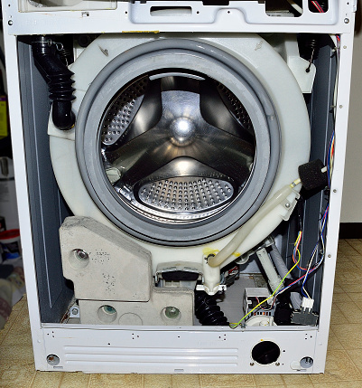 A front view of an open front load washing machine, awaiting to be serviced.