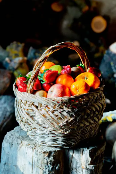 Close-up of a basket of fruits  on a trunk for chopping wood in an old cottage room.