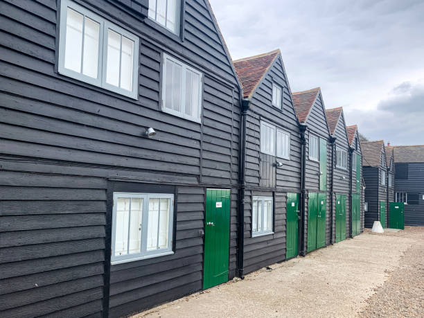 Fisherman’s huts hotel view in Whitstable, Kent, UK Dozens of fisherman black wooden huts in row along the sea cost Scandinavian Architecture moody sky 2655 stock pictures, royalty-free photos & images