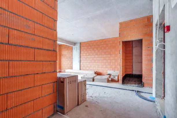 Unfinished building interior, light red orange bricks room. Repairs in the apartment. Renovation preparing in the room.