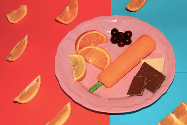 pink plate with orange ice cream and slice orange there are cherries and chocolate, creative summer meal, enjoying food