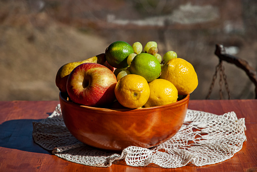 Wooden bowl with fresh fruits (grapes, pear, apple, and lemon)