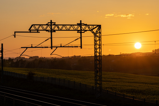 Overhead Powerlines on the railway in the sunset Railway Gantry. 2500 volts power cable