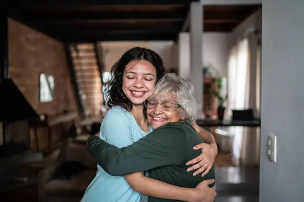 Photo of Granddaughter and grandmother hugging each other at home