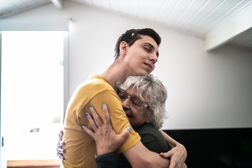 Grandmother hugging grandson at home