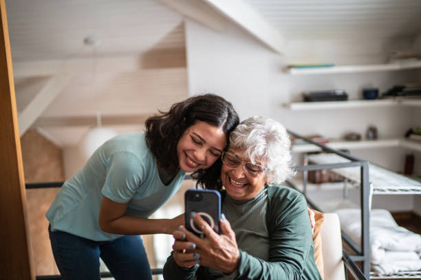 abuela y nieta usando el teléfono móvil en casa - grandmother generation gap senior adult granddaughter fotografías e imágenes de stock