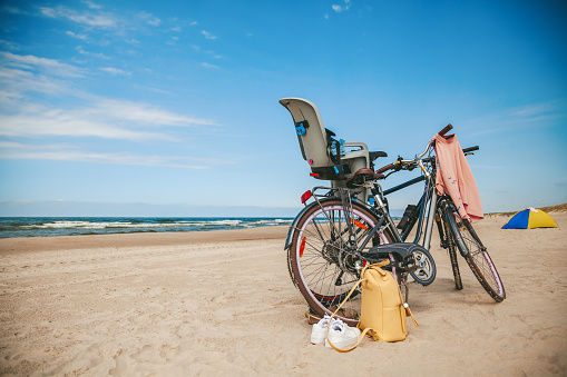 Two bicycles with child seat standing on the beach. Family activity and family journey concept.