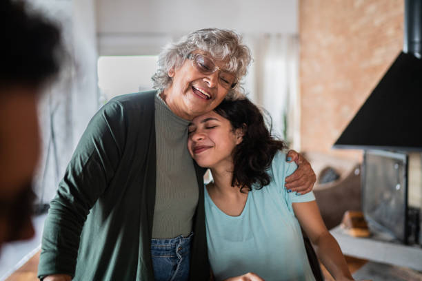 grandmother embracing granddaughter at home - breakfast eating people teens imagens e fotografias de stock