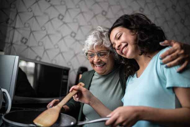 nipote e nonna che cucinano a casa - grandmother senior adult family domestic kitchen foto e immagini stock