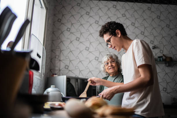 nipote e nonna che cucinano a casa - grandmother senior adult family domestic kitchen foto e immagini stock