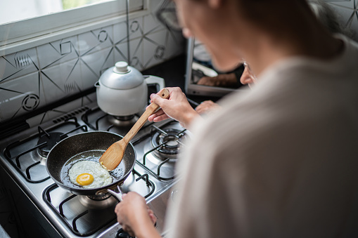 Man's hand frying an egg at home