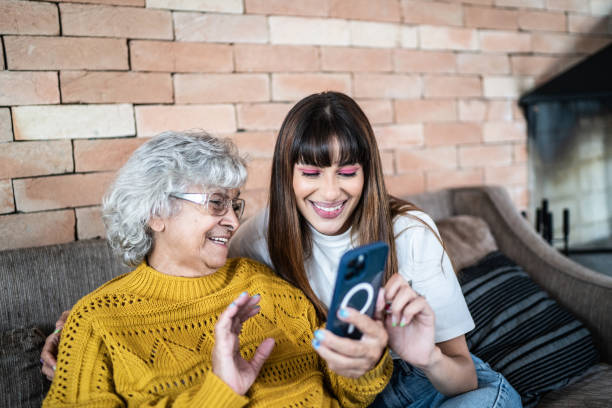 nieta y abuela usando el teléfono móvil en casa - grandmother generation gap senior adult granddaughter fotografías e imágenes de stock