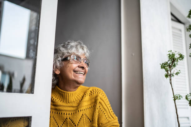 istock Contemplative senior woman looking through window at home 1395406327