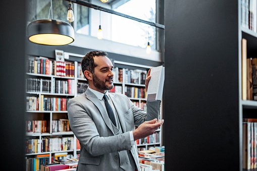 Businessman in library ,bookstore looking for book