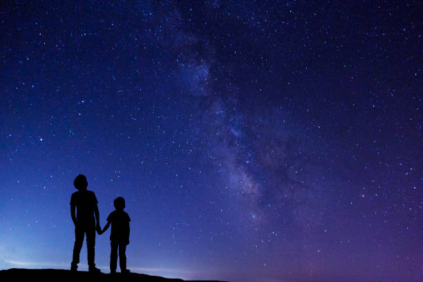 Two boys looking at Milky Way stock photo