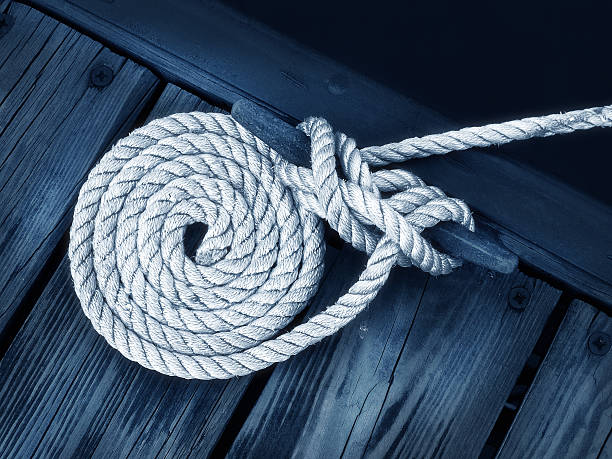 Close-up of rope tied as a nautical white boater's rope on dock anchored photos stock pictures, royalty-free photos & images