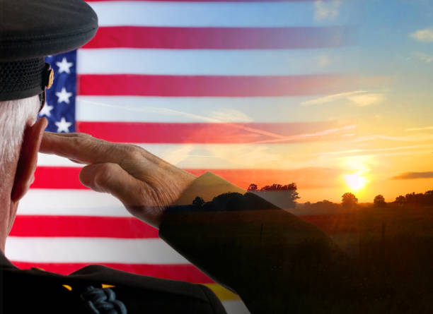 American Veteran Soldier salutes the flag with a sunrise in the background. stock photo