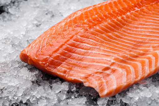 Salmon steak on ice. Chilled fish on the counter. Ice and salmon. Salmon fillet.