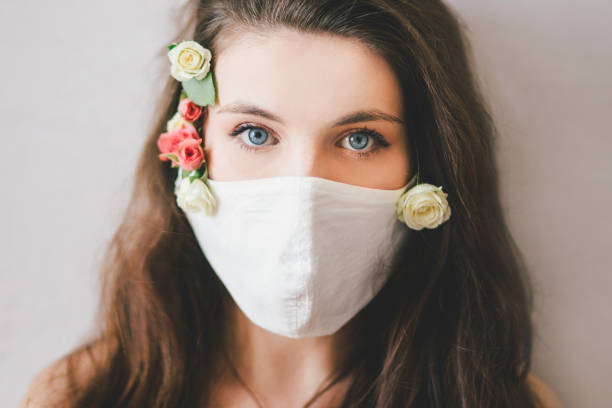 istock Young woman wearing protective mask with fresh rose flowers. 1395410732