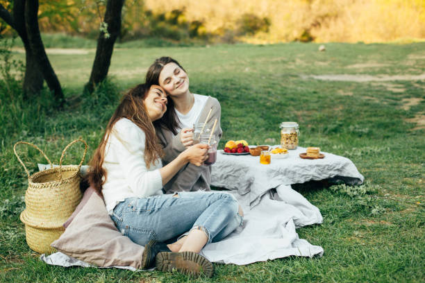 istock Two young happy women having picnic in park. 1395410910