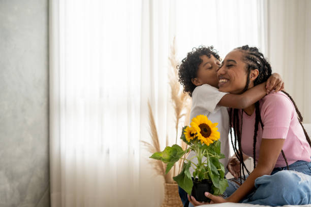 sohn überreicht seiner mutter am muttertag blumen - mothers day stock-fotos und bilder