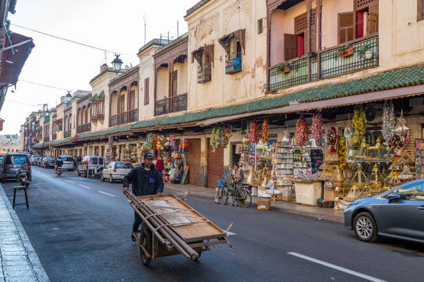 13th March, 2022 - Fez, Morocco: The Jewish quarter of Fez is a treasure trove of shops, antiquity stores along with some more well known brands and names.Workers ferry cargo and goods up and down the street all day long. You will also find a number of locals, tourists and shoppers going about their day.