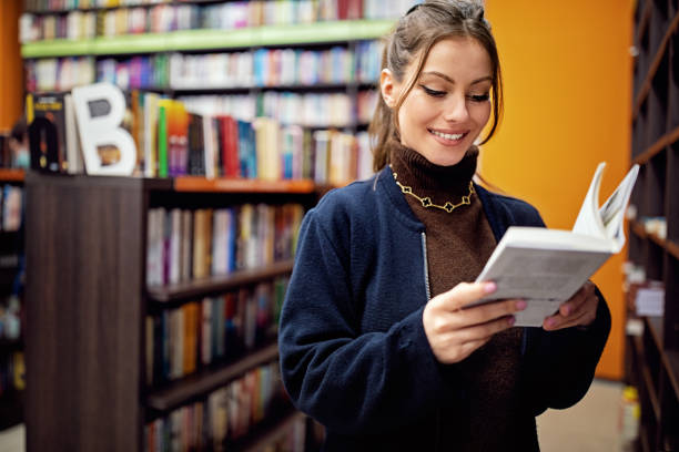 istock Woman reading a book at the library 1395415412