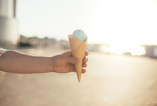 Ice-cream cone in a hand close up on wooden background.