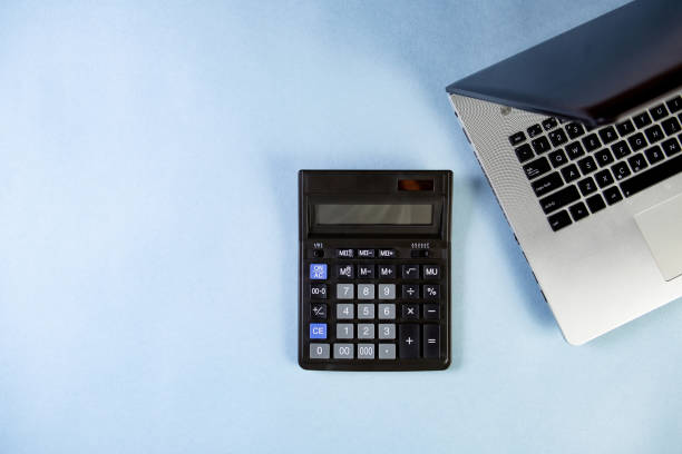 istock Flat lay of workspace with calculator and laptop on the blue background. 1395417791