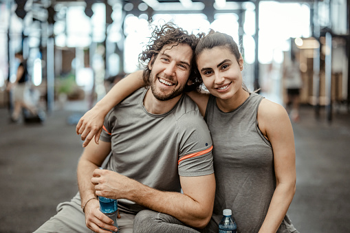Beautiful young sports couple posing in gym gym