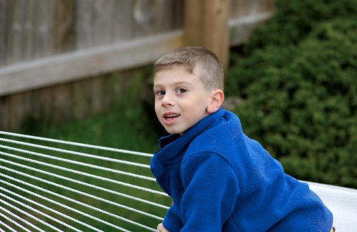 Young Boy Outdoors Cllimbing on a Hammock