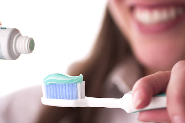 istock Toothpaste over a toothbrush with a woman in the background 139542540
