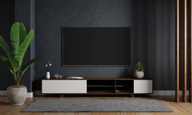 Modern mockup television tv hanging on the dark blue wall background with wooden cabinet in living room. Interior architecture and entertainment concept. 3D illustration rendering stock photo