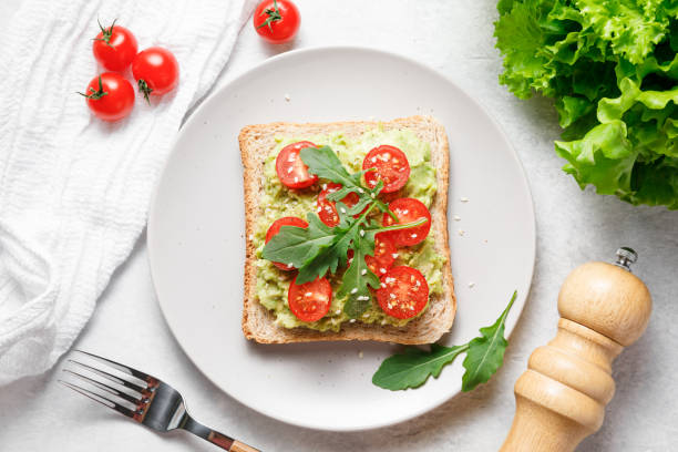 istock Avocado rye bread toast with cherry tomatoes and arugula on bright background. Healthy appetizer, breakfast, lunch or snack. Vegan food concept. Top view 1395432977