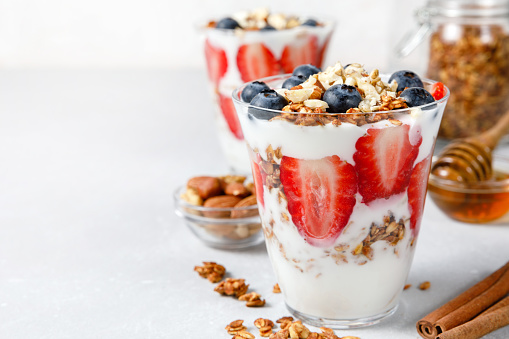 Granola Parfait with greek yogurt, oat granola, fresh berries, honey in tall glass jar. Healthy breakfast concept. Organic oat, almond and sunflower seeds. Top view, flat lay, copy space