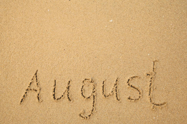 agosto - escrito a mano en la suave arena de la playa. - bienvenido agosto fotografías e imágenes de stock