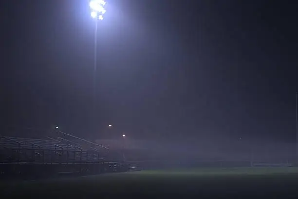 A high school football field in a foggy night.