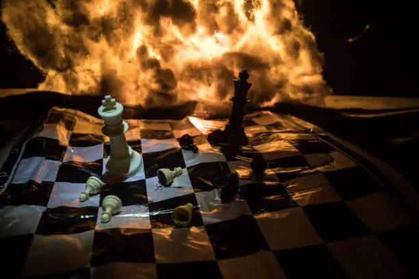 Photo of Chess board game concept of business ideas and competition and strategy ideas concep. Chess figures on a dark background with smoke and fog. Selective focus