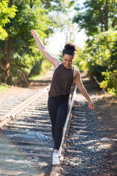 Happy Girl Wearing Sunglass Is Walking on the Railway. Blurry Background, Soft Golden Hour Light