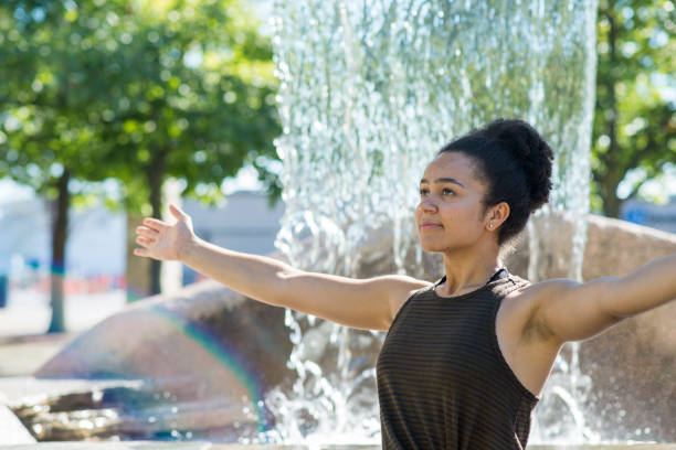 istock Young Woman Practicing Yoga by a Fountain 1395443729