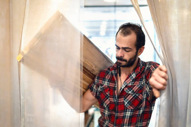 istock Carpenter carrying a wooden board over his shoulder in carpentry workshop. 1395444548