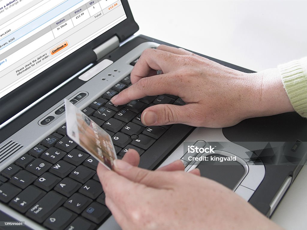 Online shopping Woman typing in credit card info on a laptop. Creditcard visible in hand. At The Edge Of Stock Photo