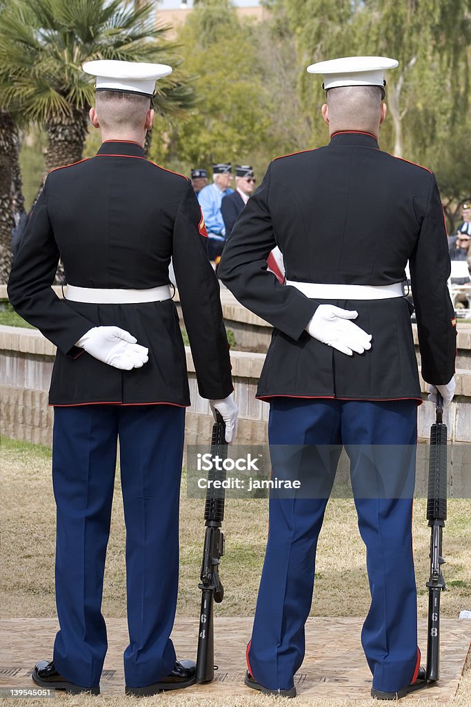 Marines Two US Marines stand guard at a WWII memorial ceremony.  WWII Veterans can be seen out of focus in the distance between the two marines. Armed Forces Stock Photo