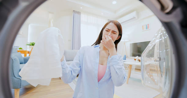 woman take clothes from washer point of view from washing machine - asian brunette long hair woman frown with stinky clothes unpleasant smell stock pictures, royalty-free photos & images