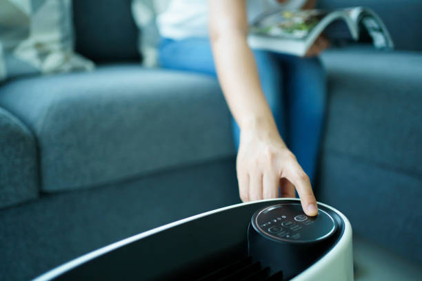 istock Woman using air purifier in living room. 1395456700