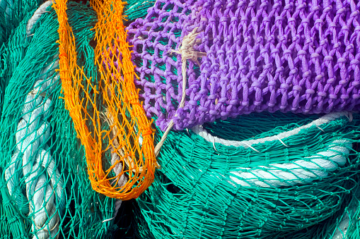 Heap of vibrant multicolored fishing nets on harbor dock, full frame view suitable for background purposes. Muros, A Coruña province, Galicia, Spain.
